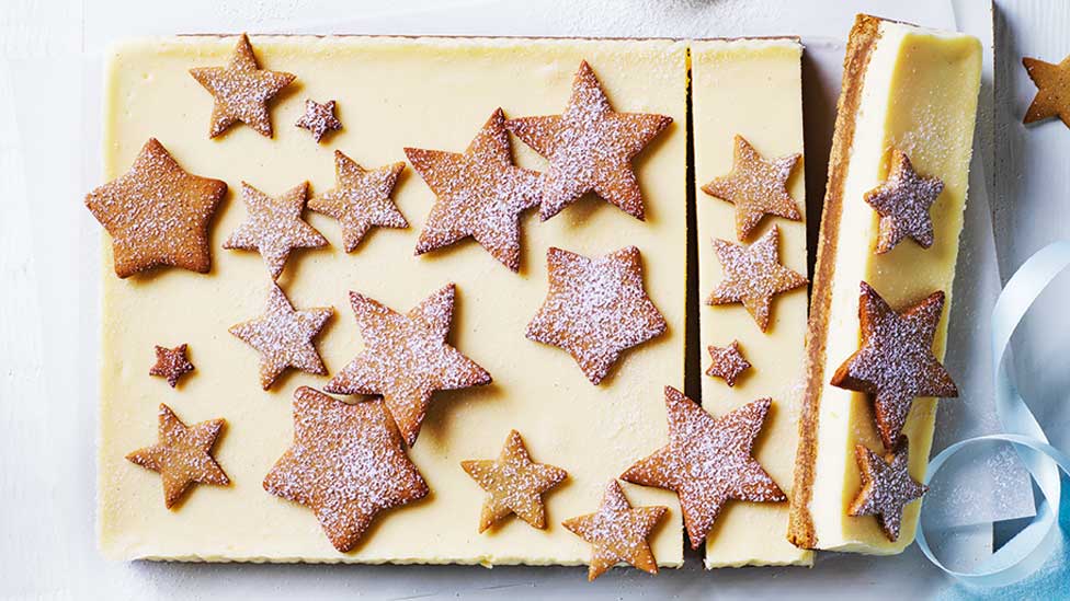 Gingerbread cheesecake decorated with gingerbread stars and cut into slices.