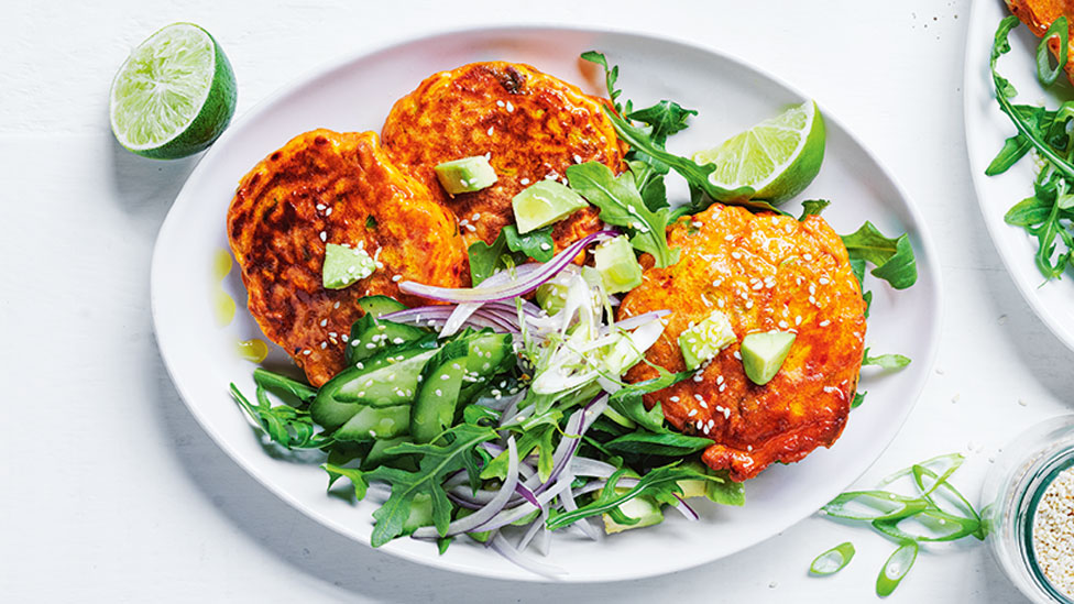 Three kimchi fritters with avocado salsa and lime wedges