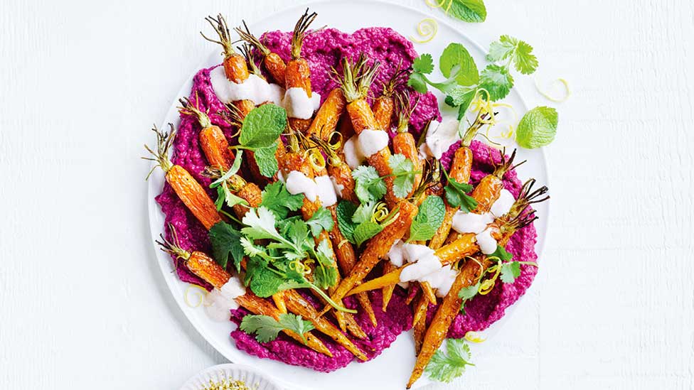 Moroccan-style salad with spiced carrots on a dish with a coriander and mint leaf garnish.