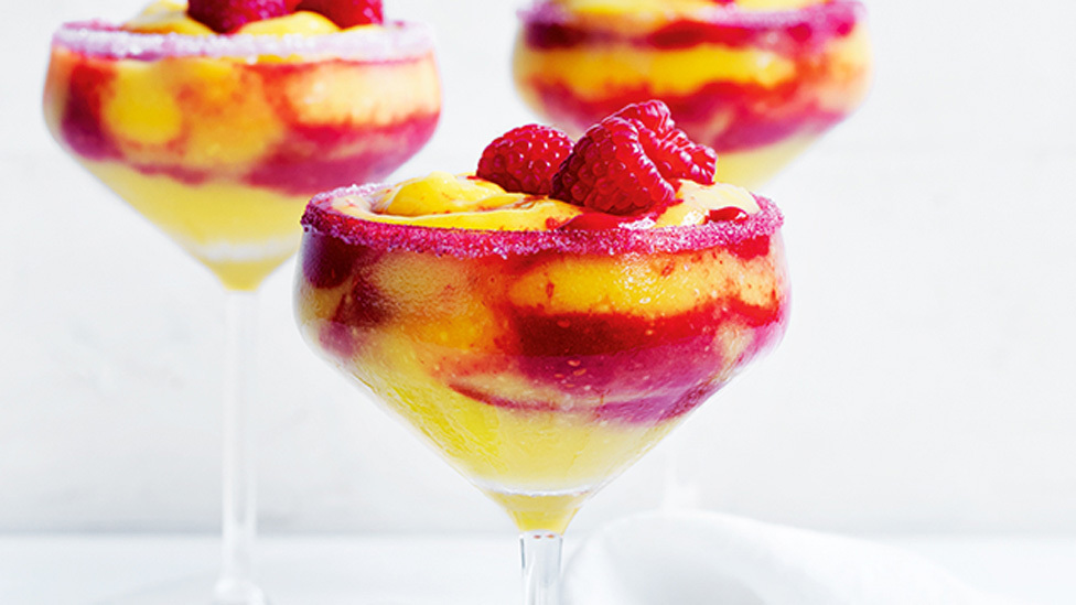 Three glasses of raspberry and mango margarita garnished with fresh raspberries.