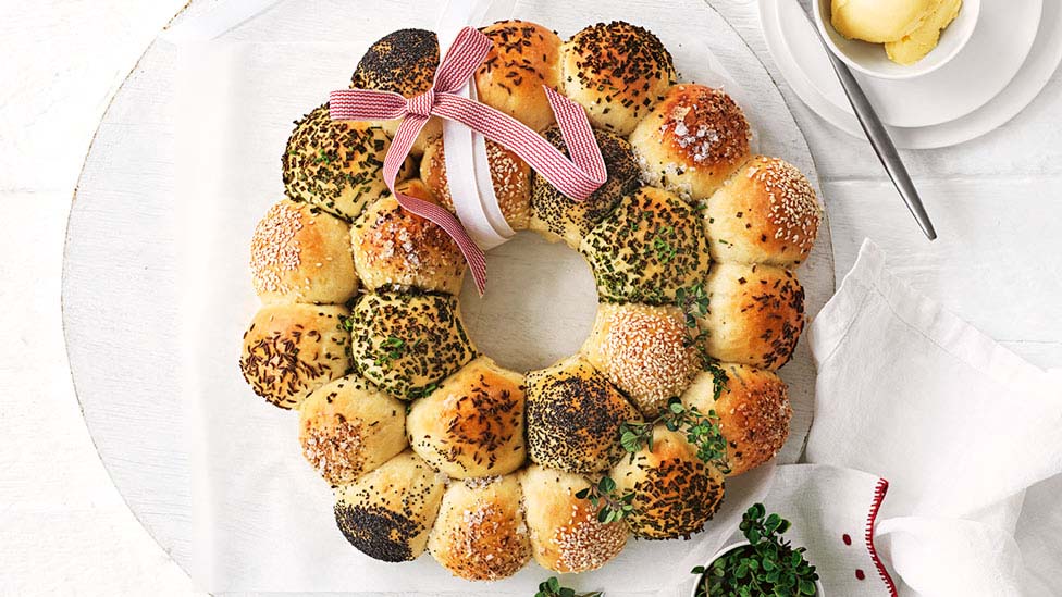 Rosemary and thyme bread roll wreath decorated with a red and white in a ribbon.