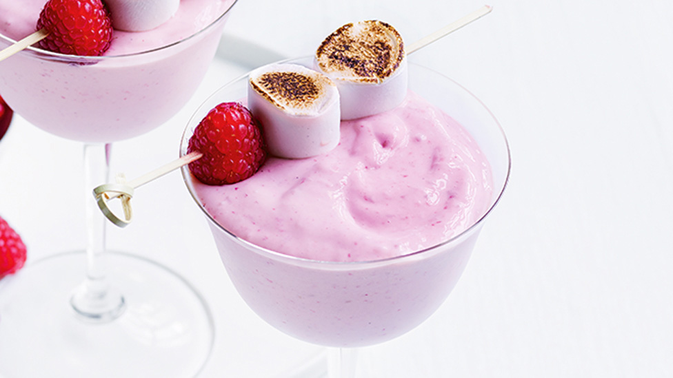 A cup of strawberries and cream marshmallow cocktail with a marshmallow skewer