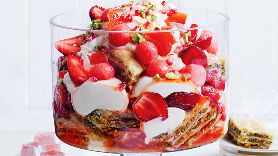 A bowl of strawberry and pistachio baklava yoghurt trifle with watermelon balls