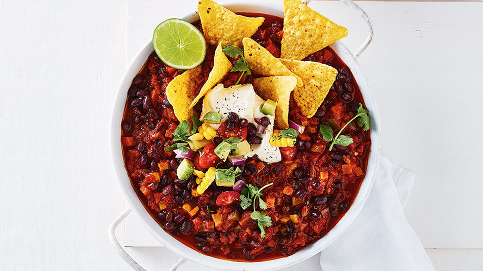 Veggie chilli with black bean salsa, corn chips and lime wedges