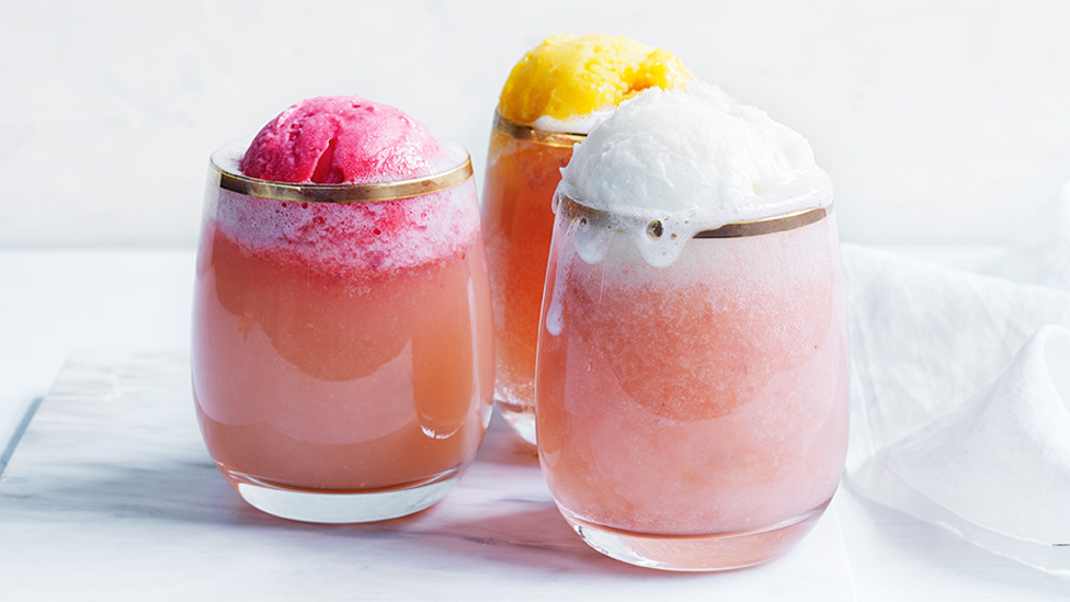 Three glasses of white peach and prosecco float with scoops of lemon, mango and berry sorbet..