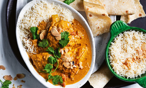A bowl of slow cooked chicken korma on rice served with naan