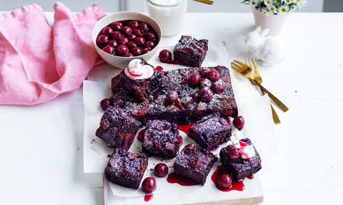 Black forest brownies served with cherries next to a pink cloth