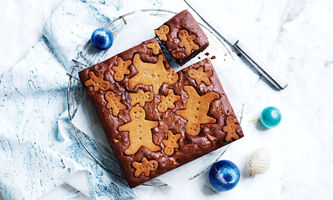 A gingerbread brownie on a blue cloth with christmas decorations