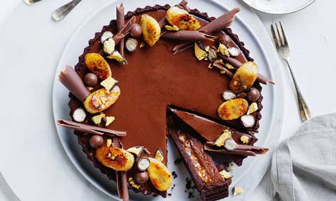 Double choc-caramel peanut tart with chocolate curls and banana slices on top