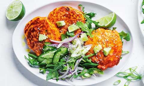 Three kimchi fritters with avocado salsa and lime wedges