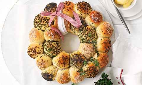 Rosemary and thyme bread roll wreath decorated with a red and white in a ribbon.
