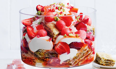 A bowl of strawberry and pistachio baklava yoghurt trifle with watermelon balls