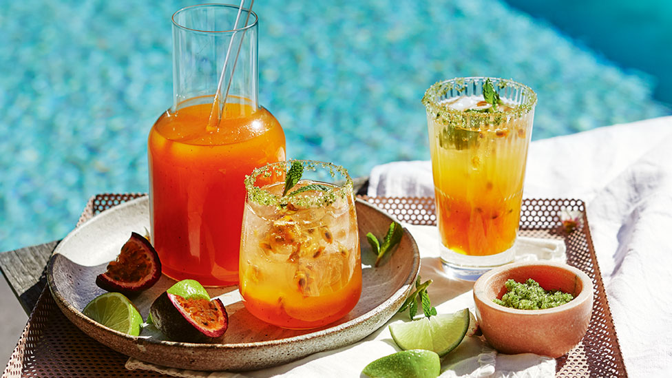 Two glasses and a jug of passionfruit and mango cooler.