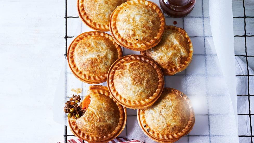 A baking tray with a stack of small beef pies