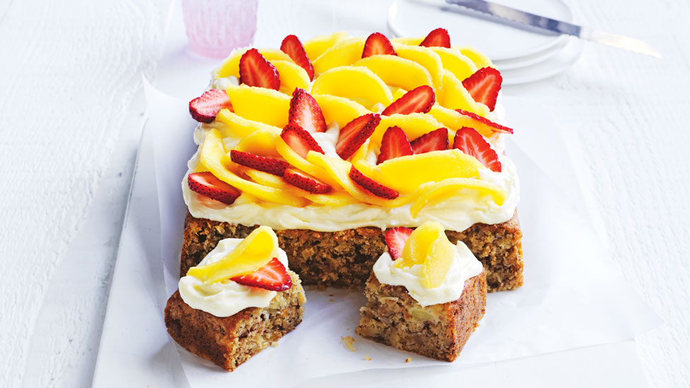 A hummingbird cake topped with mangoes and strawberries