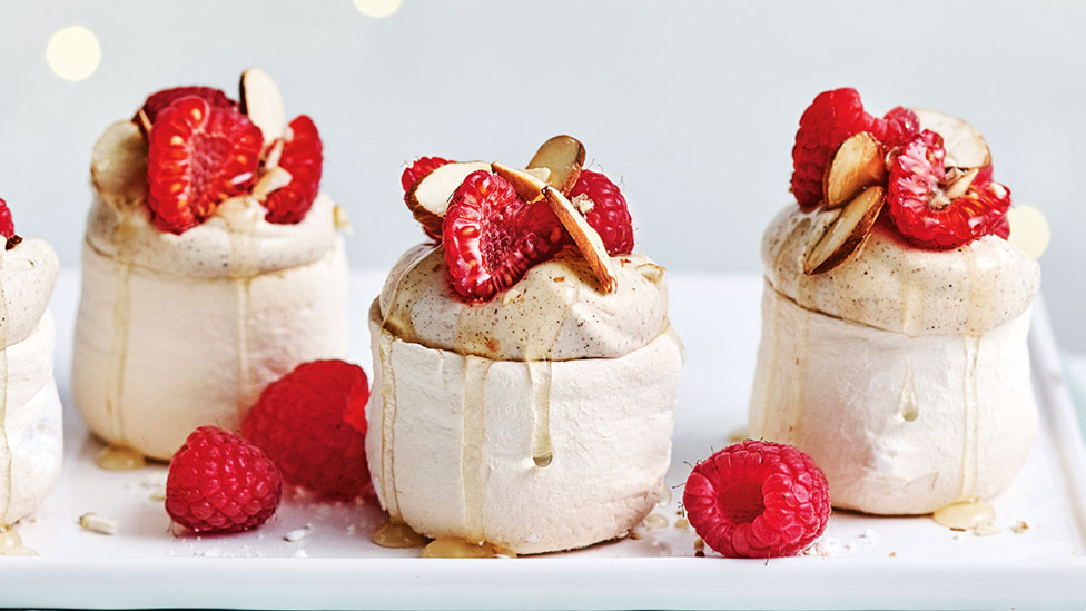 Three mini eggnog pavlovas with rum syrup and raspberry