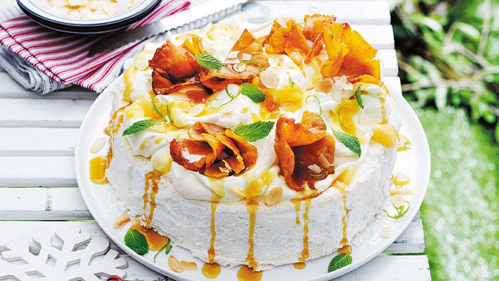 Sliced pineapple on top of a coconut and almond pavlova