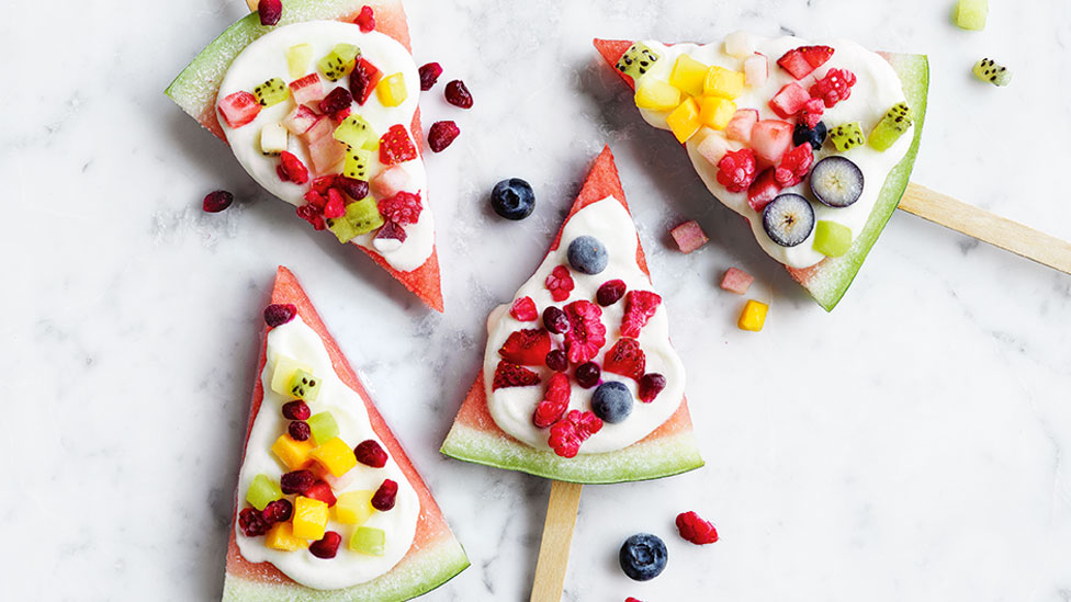 Four watermelon pops served with yoghurt and fresh fruit on top