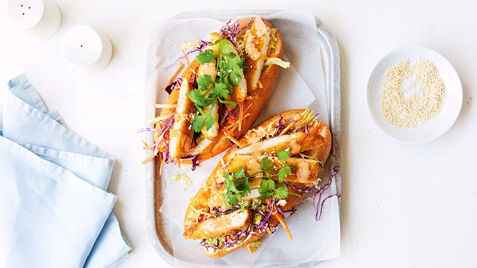 Four chicken schnitzel Banh Mi rolls on a dish.