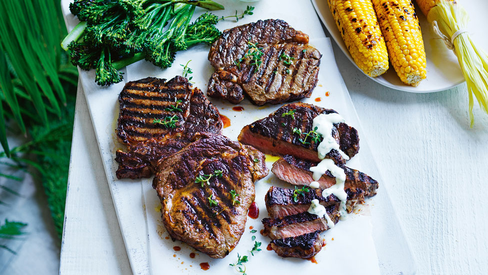 Four BBQ steaks with creamy lemon sauce and corn on the cob