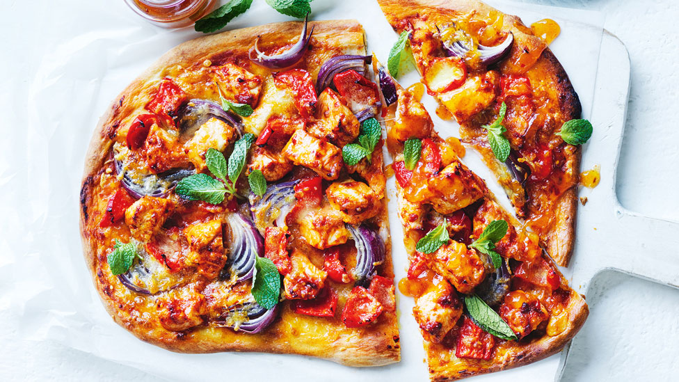 Butter chicken pizza cut into pieces