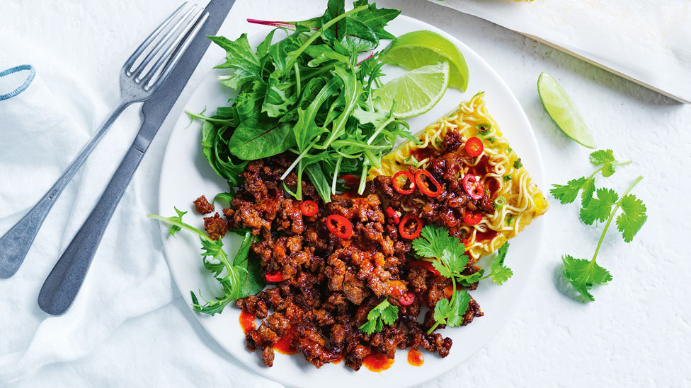 Noodle frittatas with spicy pork, lime wedges and salad leaves