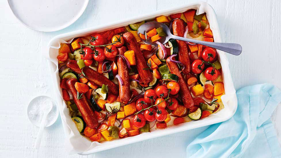 A baking tray of roasted veggies and sausages 