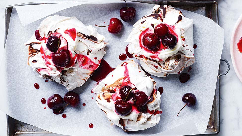 Three black forest mini pavlovas on a tray.
