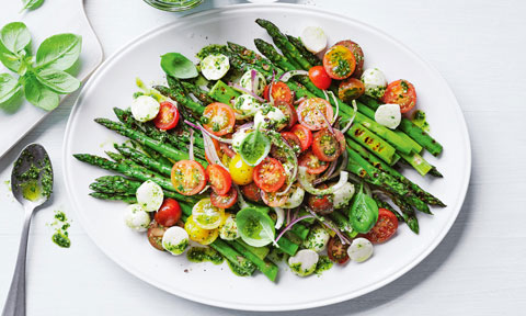 BBQ asparagus served on a big plate with cherry tomatoes and cheese on top
