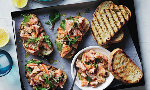 A baking tray of barbecued salmon bruschetta with herb sauce
