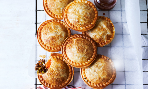 A baking tray with a stack of small beef pies