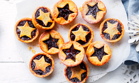 Assorted fruit mince pies laid out on a table.