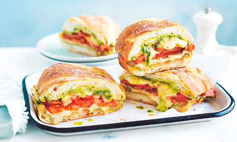 Four toasted cheese sandwiches with basil and tomato