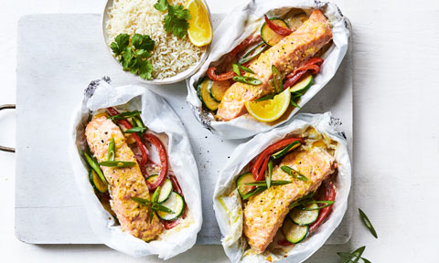 Coconut and lime salmon parcels with rice and lemon wedges