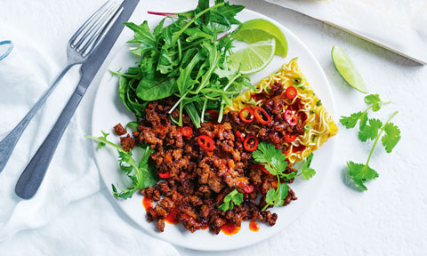 Noodle frittatas with spicy pork, lime wedges and salad leaves