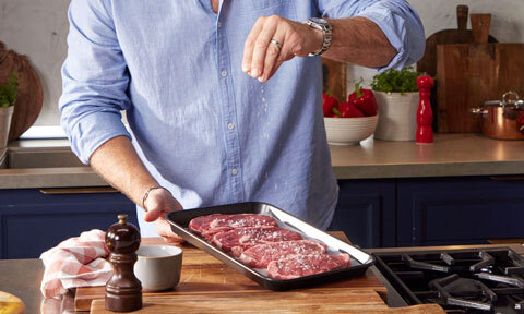 steaks being seasoned in a pan