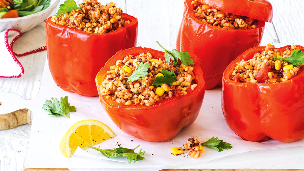 Four chicken and two-grain stuffed capsicums with salad and lemon wedges