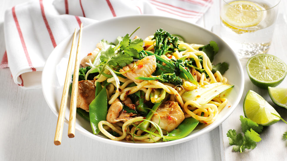 Chilli fish stir-fry with noodles with coriander leaves and onion curls