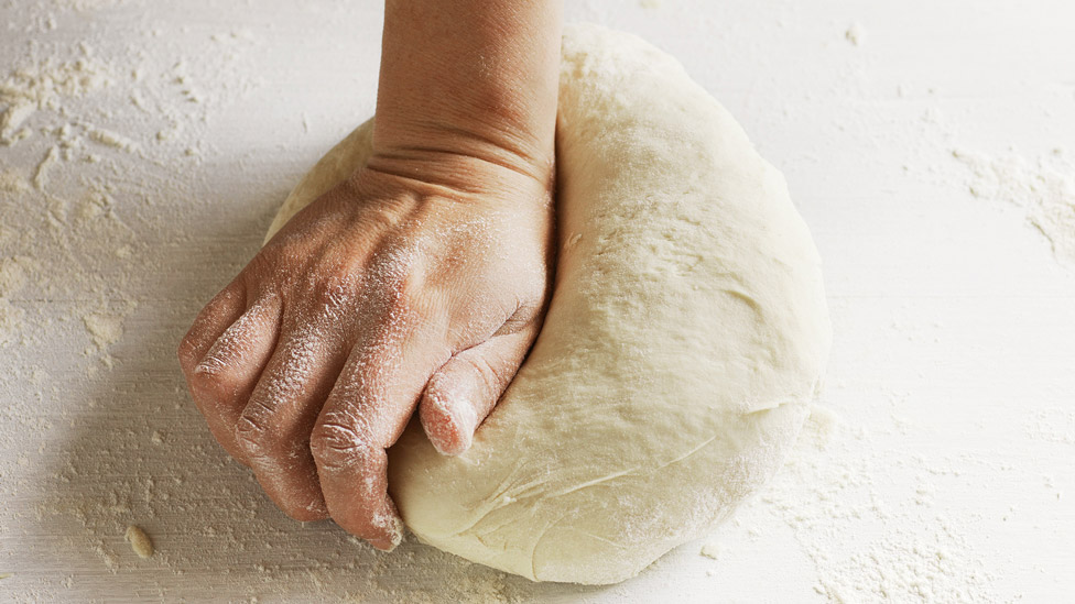 A hand kneading dough