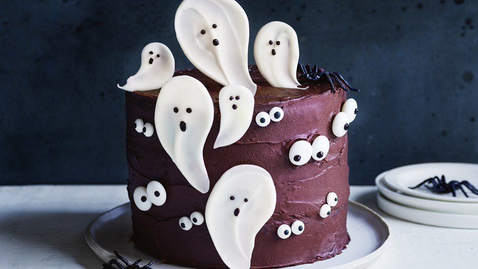 Halloween layer cake decorated with chocolate writing icing as eyes and ghosts