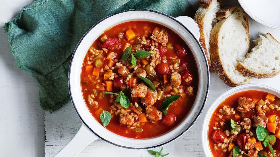 Two bowls of Italian sausage and barley soup served with toast