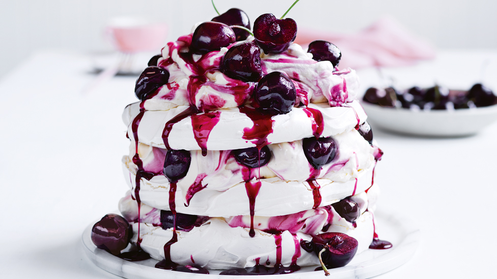 Three layers meringue and cherry torte topped with cherries