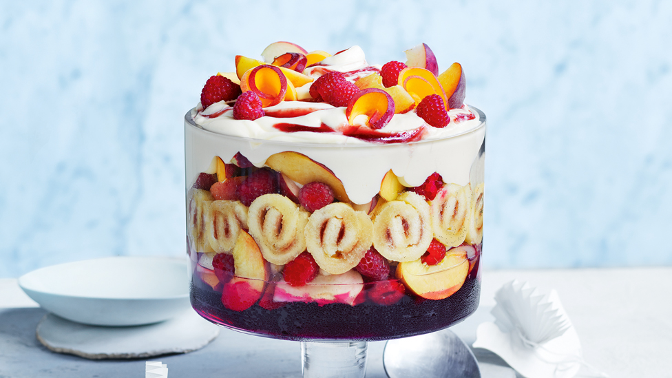 Peach Melba served in a glass dish with fresh peaches on top