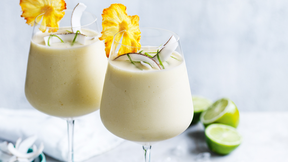 Two glasses of pineapple coconut margarita with dried pineapple flowers