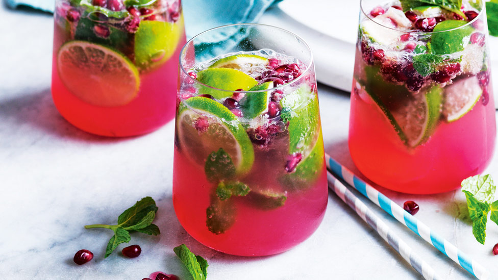 Three glasses of pomegranate gin fizz with lime slices