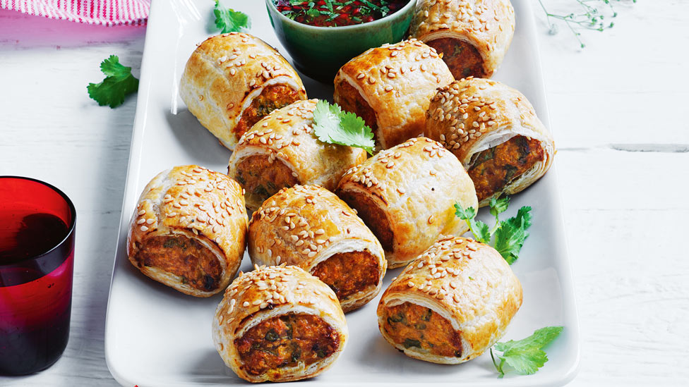 Ten red chicken curry sausage rolls on a plate