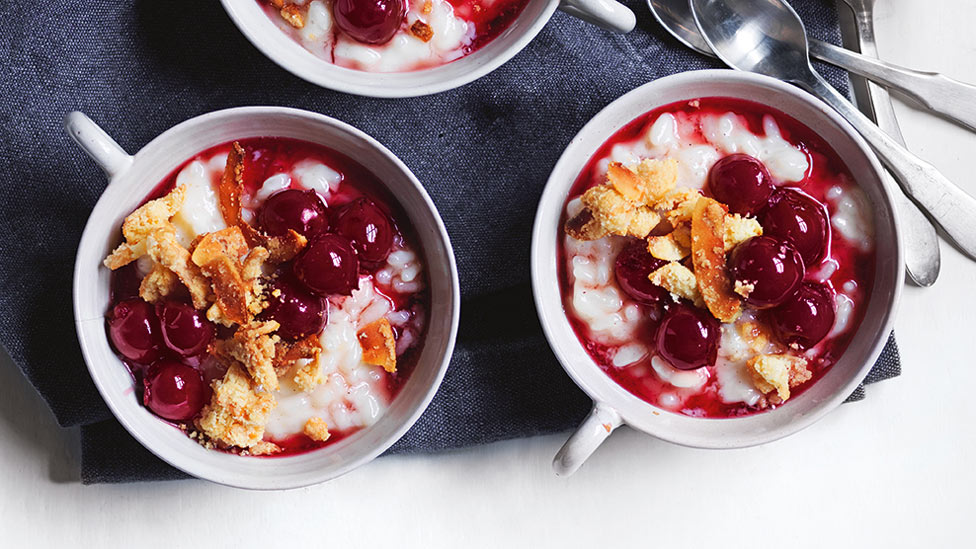 Two rice pudding with cherries and salted coconut crumble topped with cheery and coconut crumble