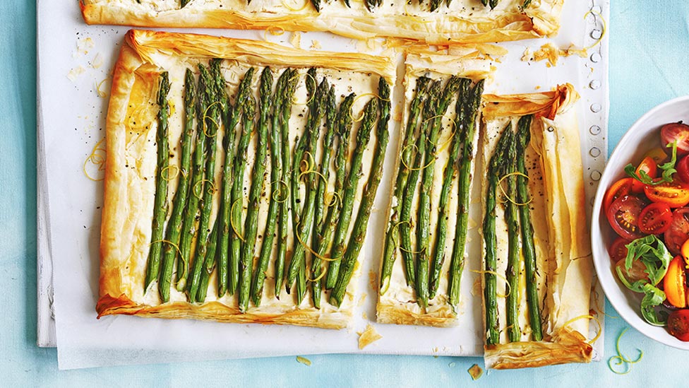 Ricotta and asparagus tarts cut in large pieces, served with tomato and rocket leaves