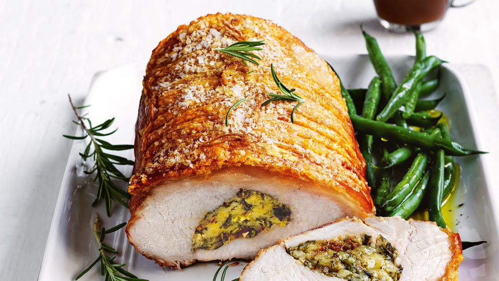 Roast pork with date and herb stuffing thickly sliced with green beans and gravy