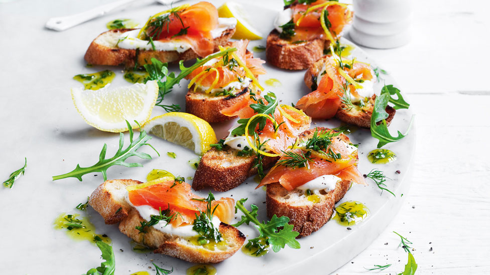 Seven smoked salmon toasts topped with herbs
